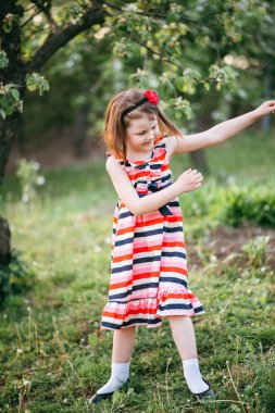 Bahçede dans çizgili elbiseli kız