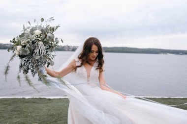 Gelin düğün buket river shore tarafından rüzgarlı gün yürüyüş ile