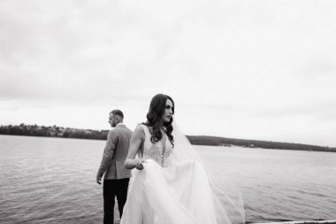 Güzel gelin beyaz elbise ve arkasında nehir kıyıya yakın yerde duran damat poz