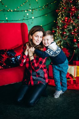 Anne ve oğlu Noel süveteri örüyorlar. Hediyelere bayılıyorlar. Yeni yıl ağacının yanında oturuyor. Hediyelerle mutlu Noeller. Kış havası