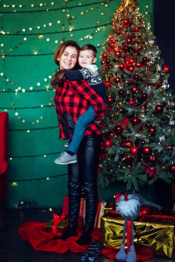 Woman with small boy posing together near decorated Christmas tree, spending great time.
