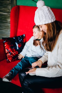 Woman and small boy having fun sitting on red sofa