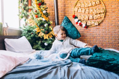 Small boy playing on bed with green pillows