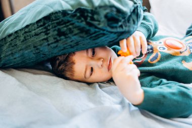 Smiling boy resting on bed with pillows