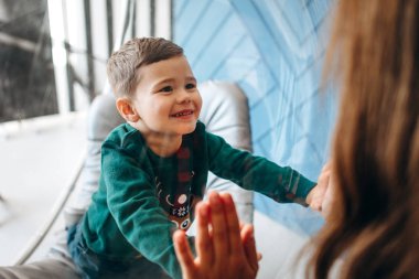 Small boy with woman holding hands through glass armchair