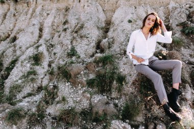 Woman posing outdoors sitting on rocks