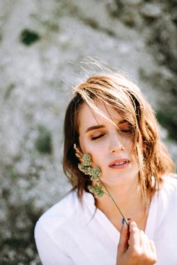 Pretty woman with natural makeup posing outdoors, playing with herbs
