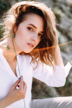 Pretty woman with natural makeup posing outdoors, playing with herbs
