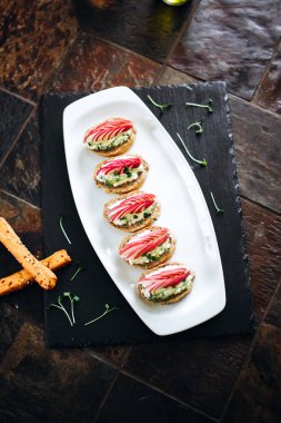 Peynirli tost, turp ve beyaz tabakta servis edilen otlar.