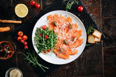 Peynirli, kaparili, roka ve domatesli dilimlenmiş somon..