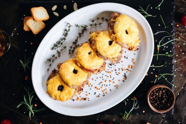 Ananas halkalı fırında domuz eti ve malzemeli peynir.