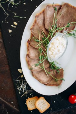 Sos ve otlarla dilimlenmiş sığır dili.