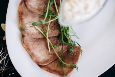 Sos ve otlarla dilimlenmiş sığır dili.