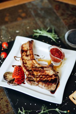 Izgara sebze ve baharatlı sosla servis edilen kuzu pirzolası.