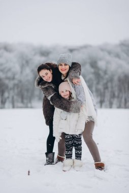 Kış parkında kızlara sarılan bir kadın.