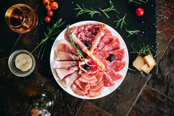 Variety of sausages, cured meat, bread sticks and olives.