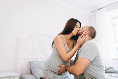 Hamilelik. Bebek bekleyen genç bir çift. Hamile kadın ve erkek yatakta.