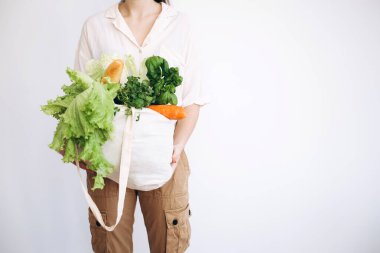Elinde sebzeli bir eco-kağıt torba. Elinde sebzeli kese kağıdı tutan genç hippi kız. Sıfır yiyecek alışverişi. eko doğal kavram