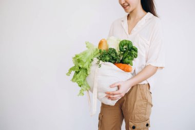Elinde sebzeli bir eco-kağıt torba. Elinde sebzeli kese kağıdı tutan genç hippi kız. Sıfır yiyecek alışverişi. eko doğal kavram