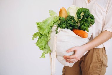 Elinde sebzeli bir eco-kağıt torba. Elinde sebzeli kese kağıdı tutan genç hippi kız. Sıfır yiyecek alışverişi. eko doğal kavram