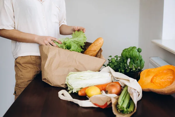 Hand with an eco paper bag with vegetables.Young hipster lifestyle girl holding paper bag with vegetables. Zero waste food shopping. eco natural concept