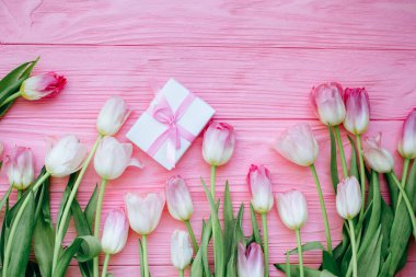 Pembe ahşap arka planda hediye kutusu olan pembe laleler.