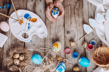 Mutlu Paskalyalar! Tahta masanın yanında renkli yumurtaları olan şirin bir çocuk.