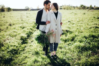 Sevgi dolu genç bir çift baharda gün batımında tarlada yürüyor.. 