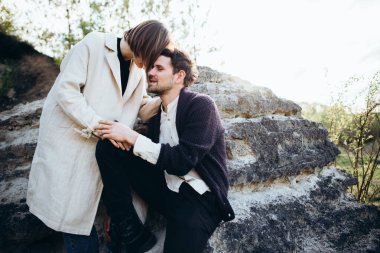 Genç hippi çift gün batımında kayaların yanında poz veriyor.