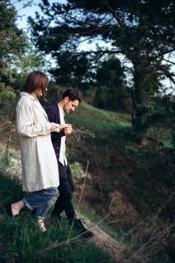 Genç hippi çift bahar ormanlarında yürüyor..
