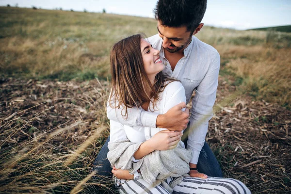 Hoş bir çift çimlerin üzerinde oturmuş öpüşüyor ve gülümsüyor. Yakın plan portre