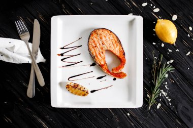 Beyaz tabakta limonlu ızgara somon bifteği.
