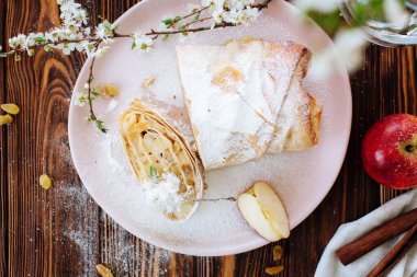 Sağlıklı ev yapımı elma turtası kuru üzüm ve tarçınlı ahşap arka planda çiçek açan meyve dallarıyla. Düz Yat. Karantina mutfağı