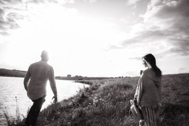 Sahilde yürüyen, kucaklaşan, arka planda gülümseyen güzel bir çift. Erkek ve kız hipster seyahati.