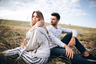 Çimlerin üzerinde oturan güzel bir çift. Erkek ve kız hipster seyahati.