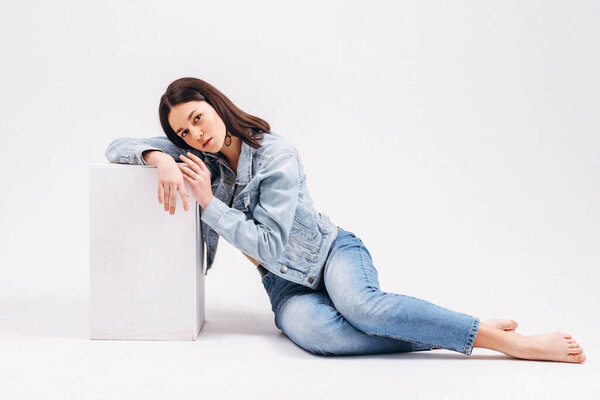 Красивая сексуальная брюнетка в джинсах и нижнем белье позирует на белом фоне
