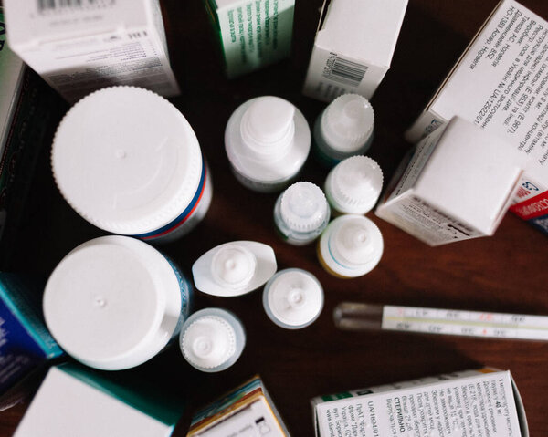 медицинские препараты таблетки и термометр для лечения коронавируса стоять на столе
