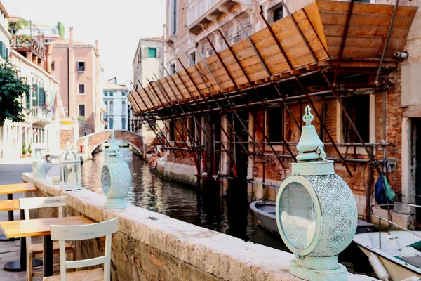 View on street cafe with romantic mint color vintage lights and water canal with bridge and buildings. Venice, Italy. — Stock Photo, Image