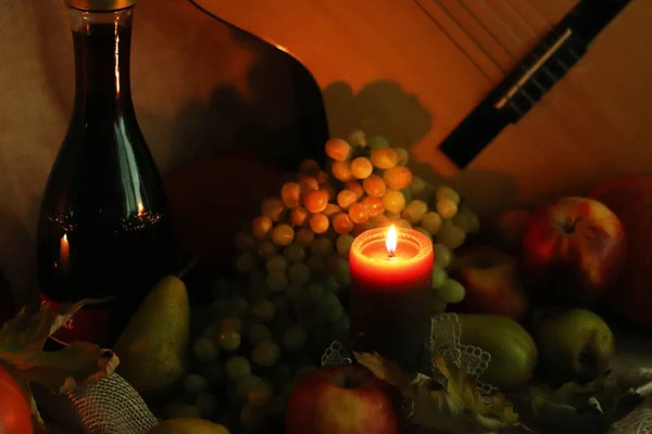 Φθινοπωρινή ζεστή σκηνή. Συνεχής συγκομιδή ζωής. Χαιρετισμούς με την κάρτα των Ευχαριστιών. Κερί φλόγα με ώριμα φρούτα και μπουκάλι κρασί — Φωτογραφία Αρχείου