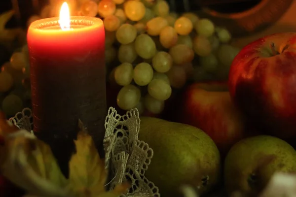 Φθινοπωρινή συγκομιδή νεκρή φύση. Ζεστό σπίτι ζεστασιά. Σύνθεση με κεριά και φρούτα: κόκκινα μήλα, πράσινα αχλάδια και σταφύλια. — Φωτογραφία Αρχείου