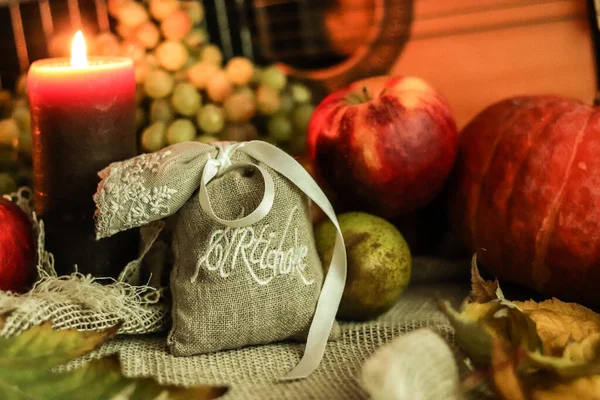 Φθινόπωρο νεκρή φύση με αγκινάρα βότανα σε σάκκο τσάντα με κορδέλα και κερί φως και φρούτα στο παρασκήνιο και κιθάρα — Φωτογραφία Αρχείου
