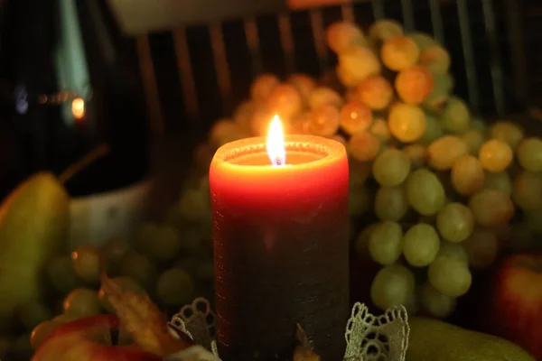 Otoño casa calidez naturaleza muerta. Vela marrón suave luz en el centro con uvas frescas, manzanas, peras y vino con guitarra Fotos de stock libres de derechos