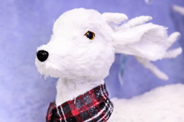 White fluffy deer toy in red checkered scarf Christmas home decoration.