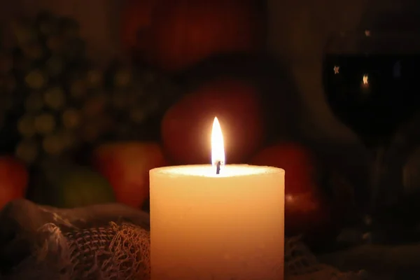 Bougie douce lumière maison chaleur automne nature morte. Jour de Thanksgiving avec des fruits et un verre de vin rouge sur fond sombre . — Photo