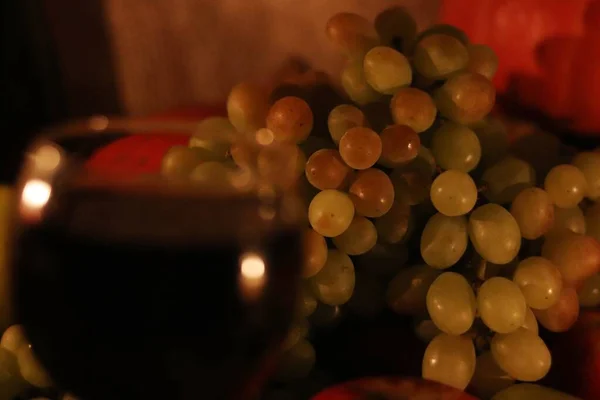Белый виноград Султана на заднем плане с размытым бокалом красного вина — стоковое фото