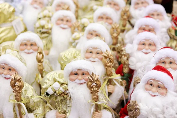 Świąteczne tło wypełnione wieloma figurkami lalek Santa Claus w czerwonych i złotych garniturach stoją w rzędach na zimowe wakacje. — Zdjęcie stockowe