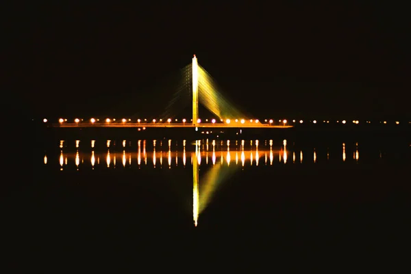 El puente se ilumina por la noche con la reflexión sobre el agua. Kiev. — Foto de Stock