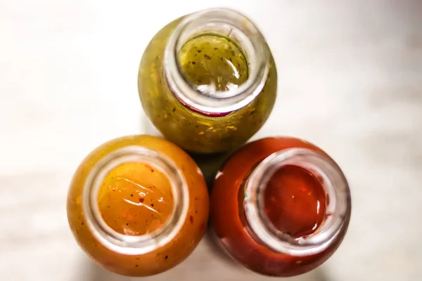 Three bottles of sauces: hot, tomatoe and herbal from above.