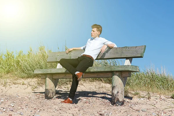 Junger Mann sitzt auf Bank — Stockfoto