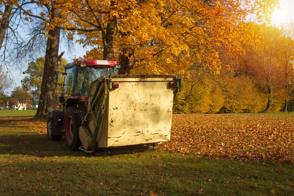 Balayeuse à vide remorquée par un tracteur dans le parc d'automne. — Photo